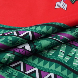 Detailed macro view of ethnic geometric print on red and green polyester fabric