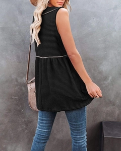 Detail of black waffle knit sleeveless top with tiered hem shown from a side back view