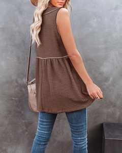 Detail of dark brown waffle knit peplum top with sleeveless design and flared hem