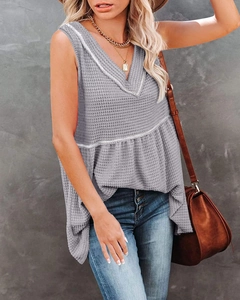 Close-up of gray waffle knit texture and V-neck sleeveless top with ruffle hem