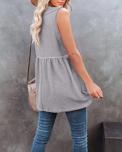 Detailed close-up of grey waffle knit sleeveless top featuring peplum hem and texture