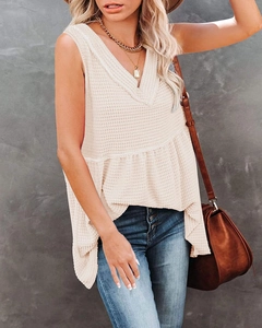 Detail of V-neck sleeveless waffle knit top with ruffled hem in off-white finish