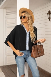 Close-up of black V-neck chiffon shirt with blue and white geometric embroidered trim