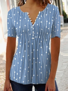 Détail d'un chemisier bleu à pois avec col en V, boutons blancs et motif lignes