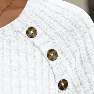 Detail of white ribbed knit fabric featuring three brown tortoiseshell button accents