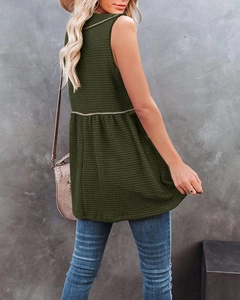 Detail of dark green waffle knit sleeveless peplum top showing textured fabric and fit