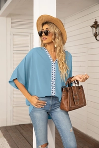 Detail of light blue chiffon blouse with V-neck and geometric embroidery for summer
