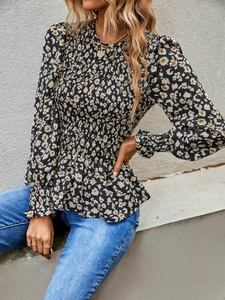 Detailed view of floral long sleeve blouse with smocked waist and ruffled hem details
