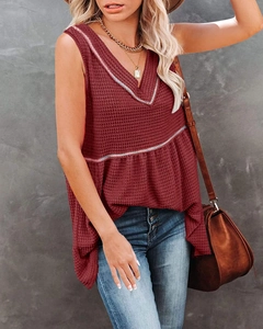 Detail of maroon waffle knit sleeveless V-neck top showing textured fabric and babydoll hem