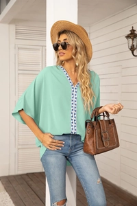 Detail of mint green V-neck chiffon blouse with blue and white embroidery on the neckline