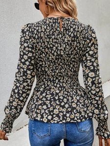 Detail of floral long sleeve blouse featuring smocking design and elastic peplum waist