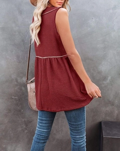 Detail of wine red waffle knit sleeveless top with textured fabric and flared hem