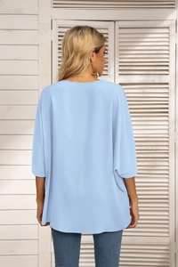 Detail view of the light blue chiffon blouse showing loose fit and soft fabric texture