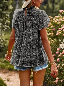 Detail of ruffle sleeves and layered hem on a black and white polka dot chiffon blouse