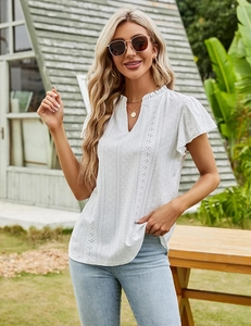Detail of white V-neck top showing intricate openwork embroidery and ruffle trim details
