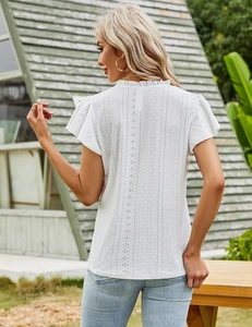 Detail of white eyelet lace texture and ruffled high neck on a summer blouse