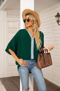 Deep green V-neck blouse featuring intricate blue geometric embroidery on the neckline