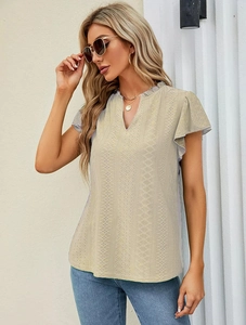 Detailed macro view of apricot V-neck top featuring intricate hollow embroidery and lace texture