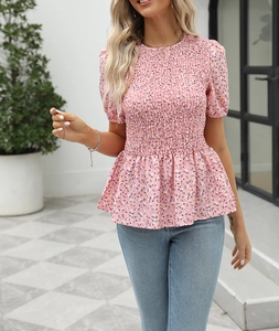 Detail of pink floral short sleeve top featuring smocked waist and peplum hem design