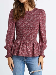 Detail of the smocking texture and floral print on a red long-sleeved peplum blouse