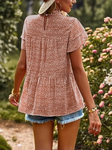 Detail of ruffle sleeves and keyhole back on a red floral chiffon blouse in a garden