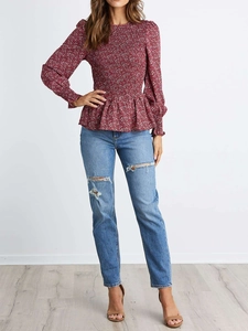 Detail of burgundy floral peplum top featuring smocked waist and long puff sleeves