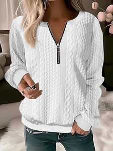 Close-up of white cable-knit sweater featuring a V-neckline with black zipper detail