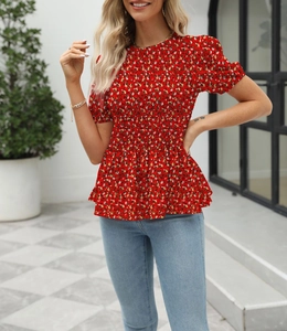 Close-up of red floral smocked top featuring a ruffled peplum hem and puff sleeves