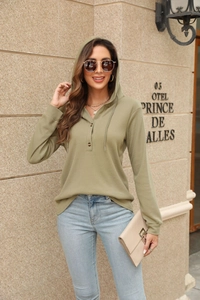 Detail of sage green waffle knit texture on long sleeve hoodie with button neckline