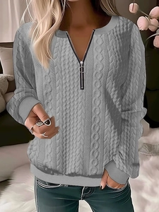 Detail of grey cable knit sweater with half-zip collar and ribbed texture on sleeves