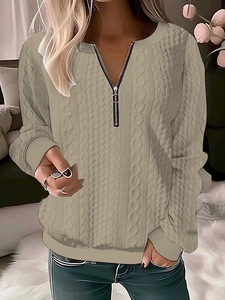 Detail of cable knit texture and metal zipper V-neck on beige long sleeve sweater