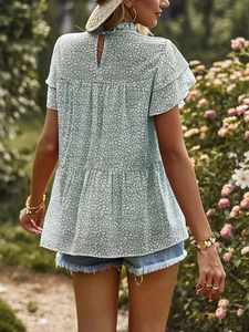 Detail of light green polka dot chiffon blouse with ruffle high neck and back cutout design
