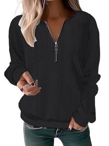 Detail of black cable knit sweater featuring a half-zip neckline and ribbed texture cuffs