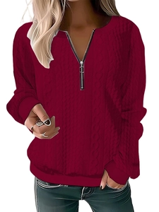 Detail of burgundy cable knit sweater featuring a silver V-neck half-zip and ribbed cuffs