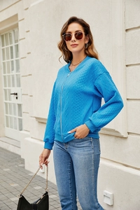 Detail of blue cable knit zip-up cardigan jacket with textured weave pattern
