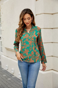 Detail of V-neck emerald green floral blouse with long sleeves and elegant draping