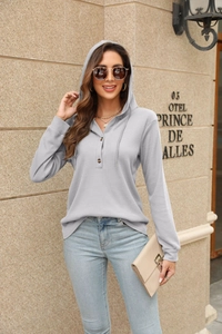 Detail of grey waffle knit hoodie featuring v-neckline and button-up front design