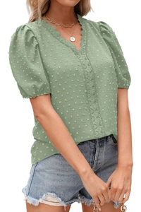 Dettaglio del bordo in pizzo sullo scollo a V e texture Swiss dot della camicetta verde
