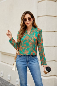 Outdoor street style of a green floral V-neck shirt with blue jeans and a woven bag