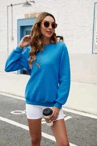 Detail of royal blue cable knit sweatshirt featuring a functional half-zip neckline