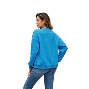Close-up of blue diamond pattern knit sweater with ribbed cuffs and texture details