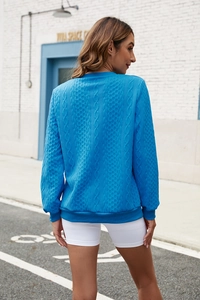 Detailed view of women's blue knit pullover featuring 3D diamond texture and ribbed cuffs