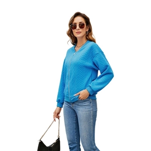 Detail of bright blue cable knit zip-up cardigan with textured weave and ribbed cuffs