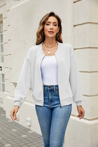 Detailed close-up of white cable knit texture and metal zipper on women's jacket