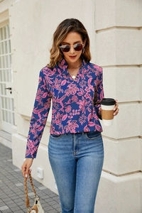 Close-up of pink floral patterns on navy V-neck long sleeve blouse on street