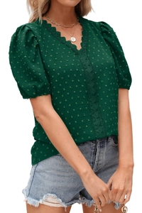Dettaglio del tessuto a pois verde scuro con pizzo all'uncinetto e scollo a V