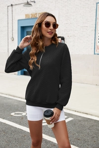 Detail of black cable-knit sweatshirt featuring a metal half-zip and ribbed cuffs