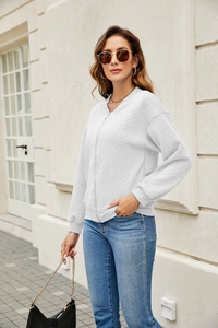 Detail of white cable knit zip-up baseball jacket featuring ribbed collar and metal zipper