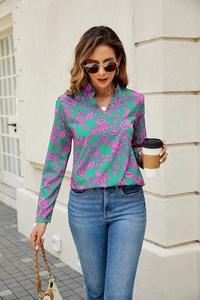 Detail of vibrant green V-neck floral blouse featuring pink leaf patterns and long sleeves