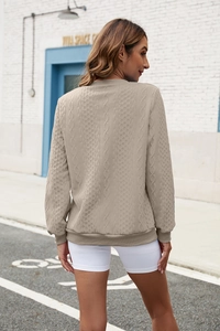 Close-up of khaki cable knit sweatshirt with complex textured pattern and ribbed cuffs